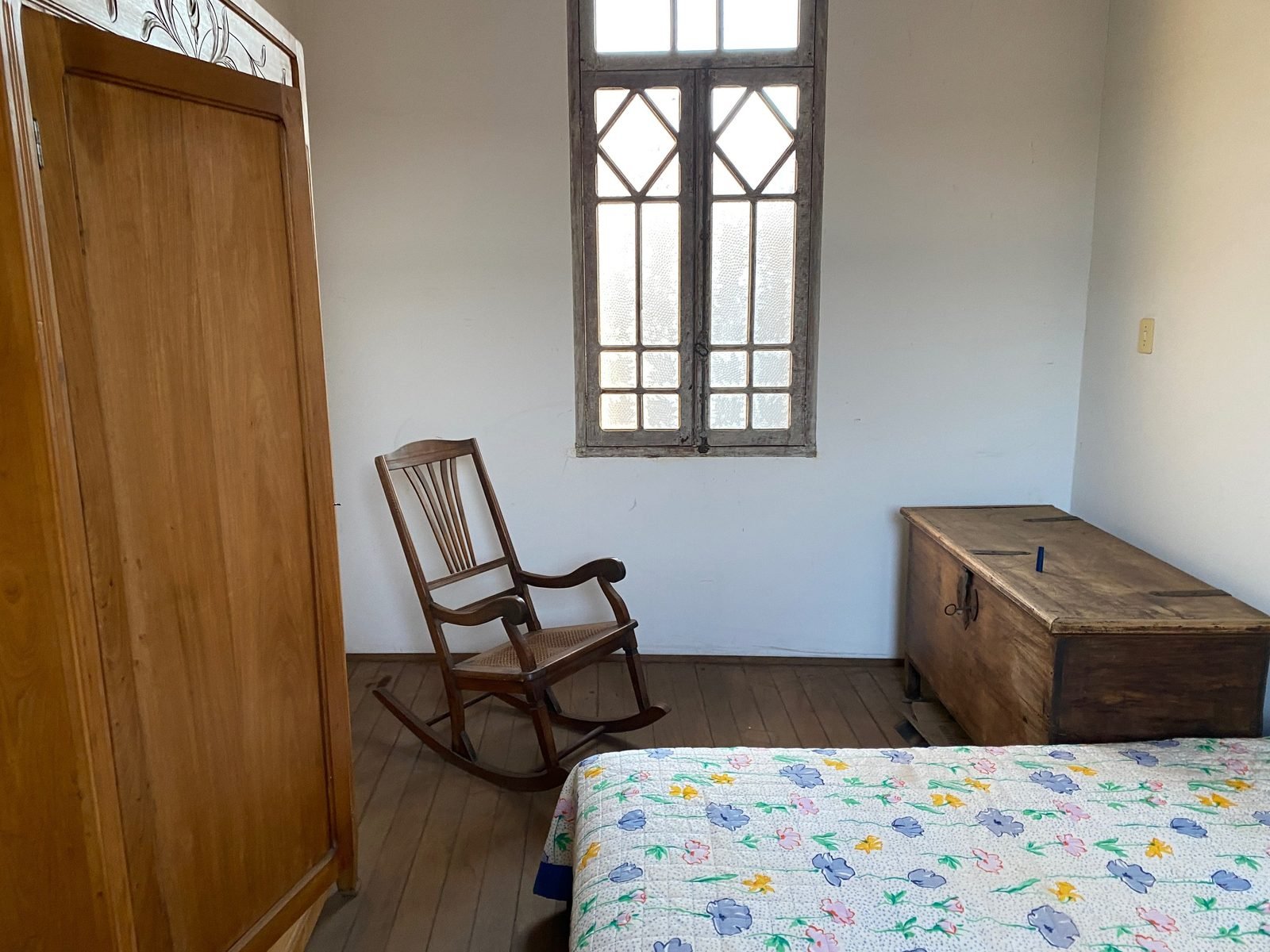 Bedroom with rocking chair, wooden chest and tall window