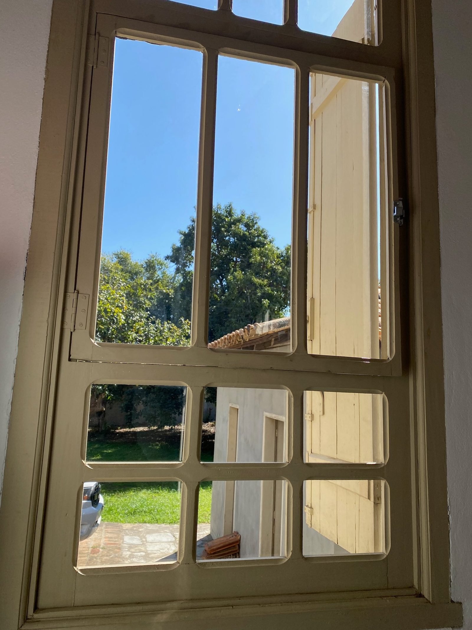 Interior window with white-painted wooden frames, open to the garden